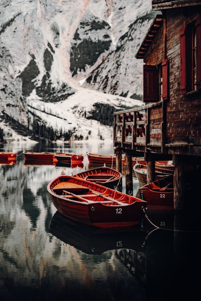 白天在白雪覆盖的山附近的水面上的棕色木船
